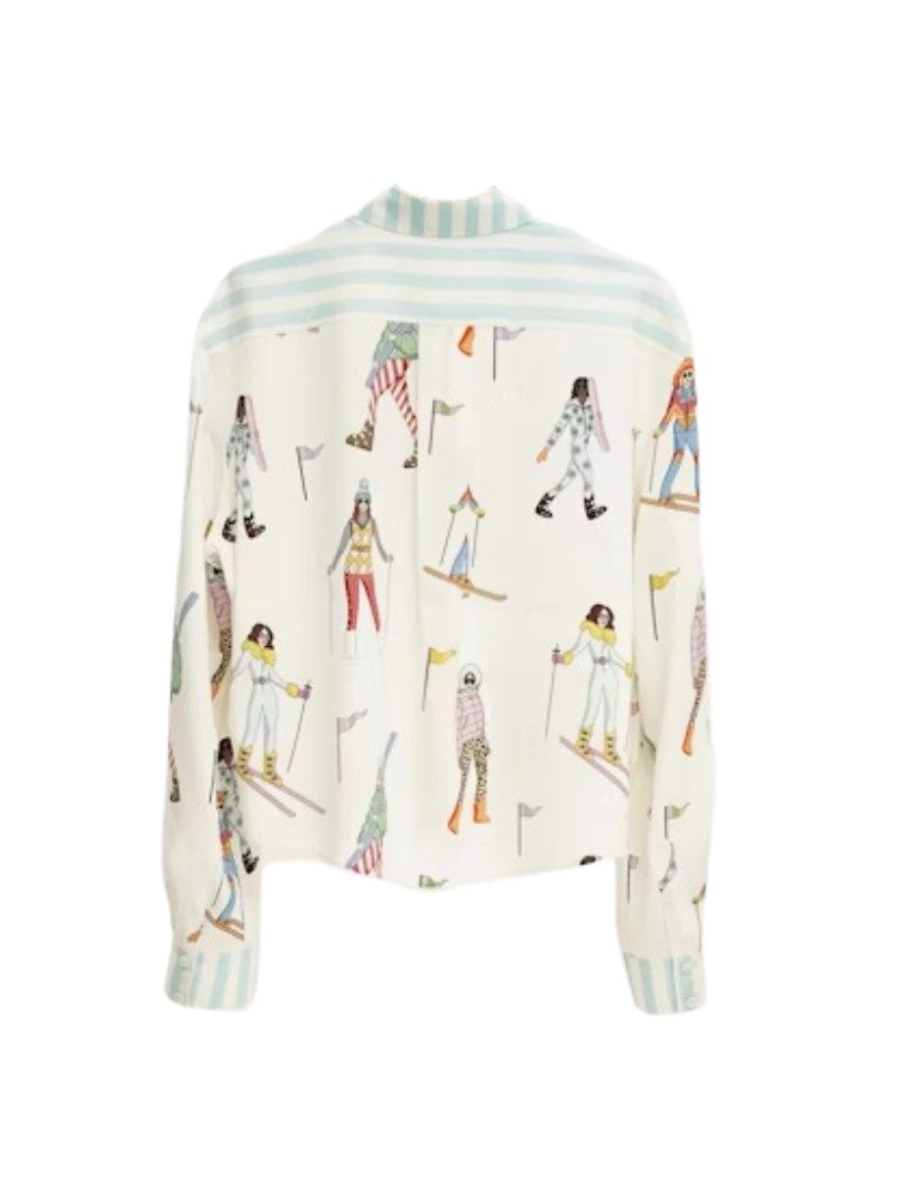 Bluse Herzensangelegenheit in weiß. Diese Seidenbluse mit Hemdkragen ist ein echtes Highlight. Sie hat eine verkürzte Länge und einen verspielten Ski-Print mit bunten Skifahrerinnen. Die Hemdbluse hat linierte Manschetten mit zwei Knöpfen und eine durchgehende Knopfleiste.