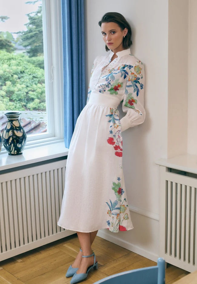 Kleid Dea Kudibal AlondraDEA hat einen Frühlingsblumenprint und einen Stehkragen, Oberteil ist figurbetont geschnitten und das Kleid hat einen Taillenbund mit  Bindegürtel in weiss mit bunten Blumen aus Leinen mit Taschen 