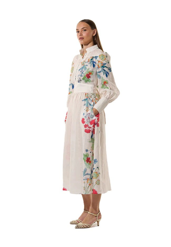 Kleid Dea Kudibal AlondraDEA hat einen Frühlingsblumenprint und einen Stehkragen, Oberteil ist figurbetont geschnitten und das Kleid hat einen Taillenbund mit  Bindegürtel in weiss mit bunten Blumen aus Leinen 