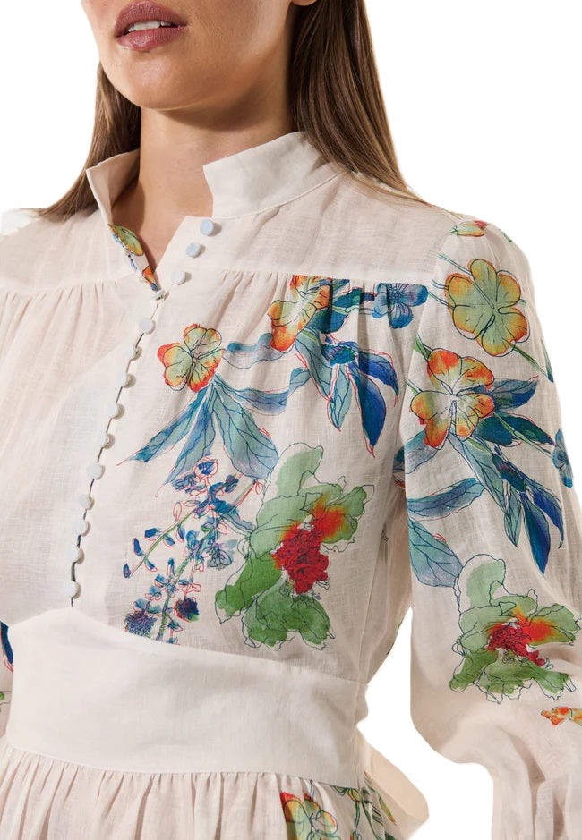 Kleid Dea Kudibal AlondraDEA hat einen Frühlingsblumenprint und einen Stehkragen, Oberteil ist figurbetont geschnitten und das Kleid hat einen Taillenbund mit  Bindegürtel in weiss mit bunten Blumen aus Leinen mit Taschen 