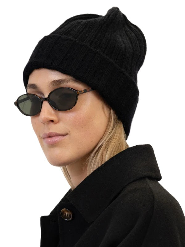 Beanie Laura von Anna v Berg in Schwarz. Diese hochwertige Beanie aus 100 % Kaschmir begeistert mit ihrem besonders weichen Griff und sorgt für ein angenehm kuscheliges Tragegefühl. Das zeitlose Rippstrick-Design macht sie zu einem stilvollen Begleiter für die kühlen Tage. Ein hochwertiges Accessoire, das Wärme und lässige Eleganz perfekt miteinander verbindet. 