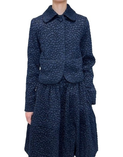 Jacke Odeeh in Nightflight. Edle Jacke aus einer genoppten Ware in dunkelblau. Die Jacke hat einen Kragen mit einem tonigen Knopf und eine verdeckte Knopfleiste. Der Kragen ist leicht abgerundet. Die Jacke hat Stecktaschen auf der Vorderseite. Sie ist körpernah geschnitten.