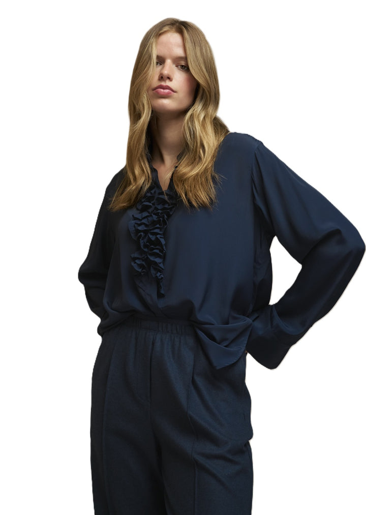 Dunkelblaue Seidenbluse Jessi von der Marke 0039 Italy mit Hemdblusenkragen und Rüschendetails. Die Bluse hat lange Ärmel und eine verdeckte Knopfleiste.