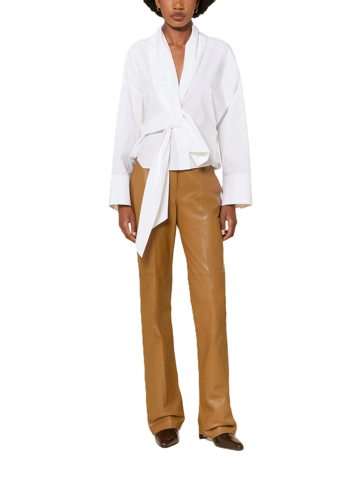 Bluse Dorothee Schumacher POPLIN POWER blouse in weiß. Diese Bluse ist ein richtiges It-Piece. Sie vereint modische Wickeloptik mit femininem Schnitt perfekt. Die Bluse hat einen Schalkragen und lange Ärmel. An den Manschetten befinden sich schöne Knöpfe. Die Ärmel sind weit und die Schultern überschnitten. Auf der Rückseite ist die Bluse eingeschlagen und der Saum mit einem elastischen Band versehen.