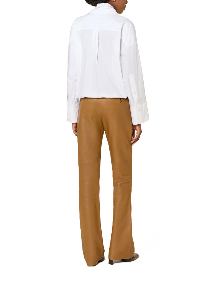 Bluse Dorothee Schumacher POPLIN POWER blouse in weiß. Diese Bluse ist ein richtiges It-Piece. Sie vereint modische Wickeloptik mit femininem Schnitt perfekt. Die Bluse hat einen Schalkragen und lange Ärmel. An den Manschetten befinden sich schöne Knöpfe. Die Ärmel sind weit und die Schultern überschnitten. Auf der Rückseite ist die Bluse eingeschlagen und der Saum mit einem elastischen Band versehen.