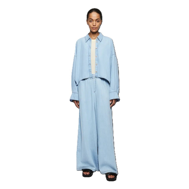 Bluse Drykorn OSHIA 10 in blau. OSHIA ist eine weit geschnittene Hemdbluse mit überschnittener Schulter und überlangen Ärmeln. Der Indigo Denim hat eine helle Farbgebung und einen leichten Wascheffekt was ihn zu einem echten Everyday Essential macht. Die Bluse hat einen Kragen und eine verdeckte Knopfleiste und ist vorne kürzer geschnitten als hinten.