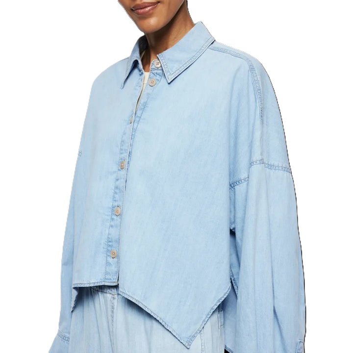 Bluse Drykorn OSHIA 10 in blau. OSHIA ist eine weit geschnittene Hemdbluse mit überschnittener Schulter und überlangen Ärmeln. Der Indigo Denim hat eine helle Farbgebung und einen leichten Wascheffekt was ihn zu einem echten Everyday Essential macht. Die Bluse hat einen Kragen und eine verdeckte Knopfleiste und ist vorne kürzer geschnitten als hinten.