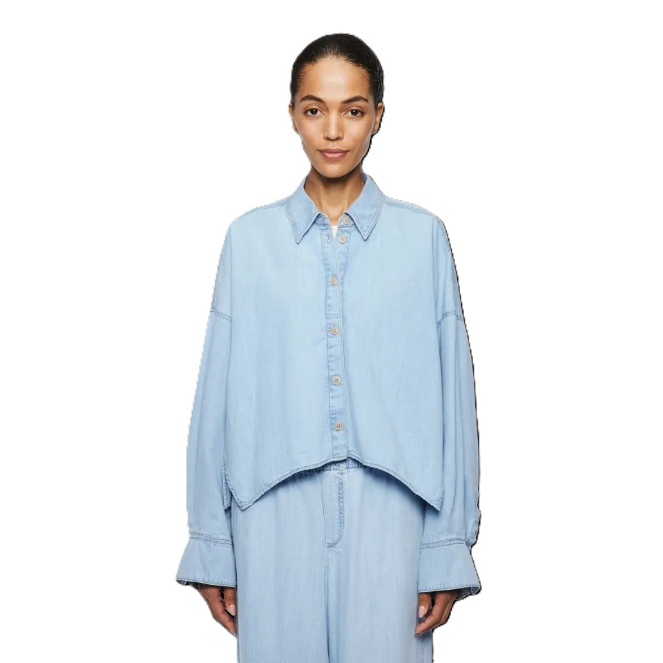 Bluse Drykorn OSHIA 10 in blau. OSHIA ist eine weit geschnittene Hemdbluse mit überschnittener Schulter und überlangen Ärmeln. Der Indigo Denim hat eine helle Farbgebung und einen leichten Wascheffekt was ihn zu einem echten Everyday Essential macht. Die Bluse hat einen Kragen und eine verdeckte Knopfleiste und ist vorne kürzer geschnitten als hinten.