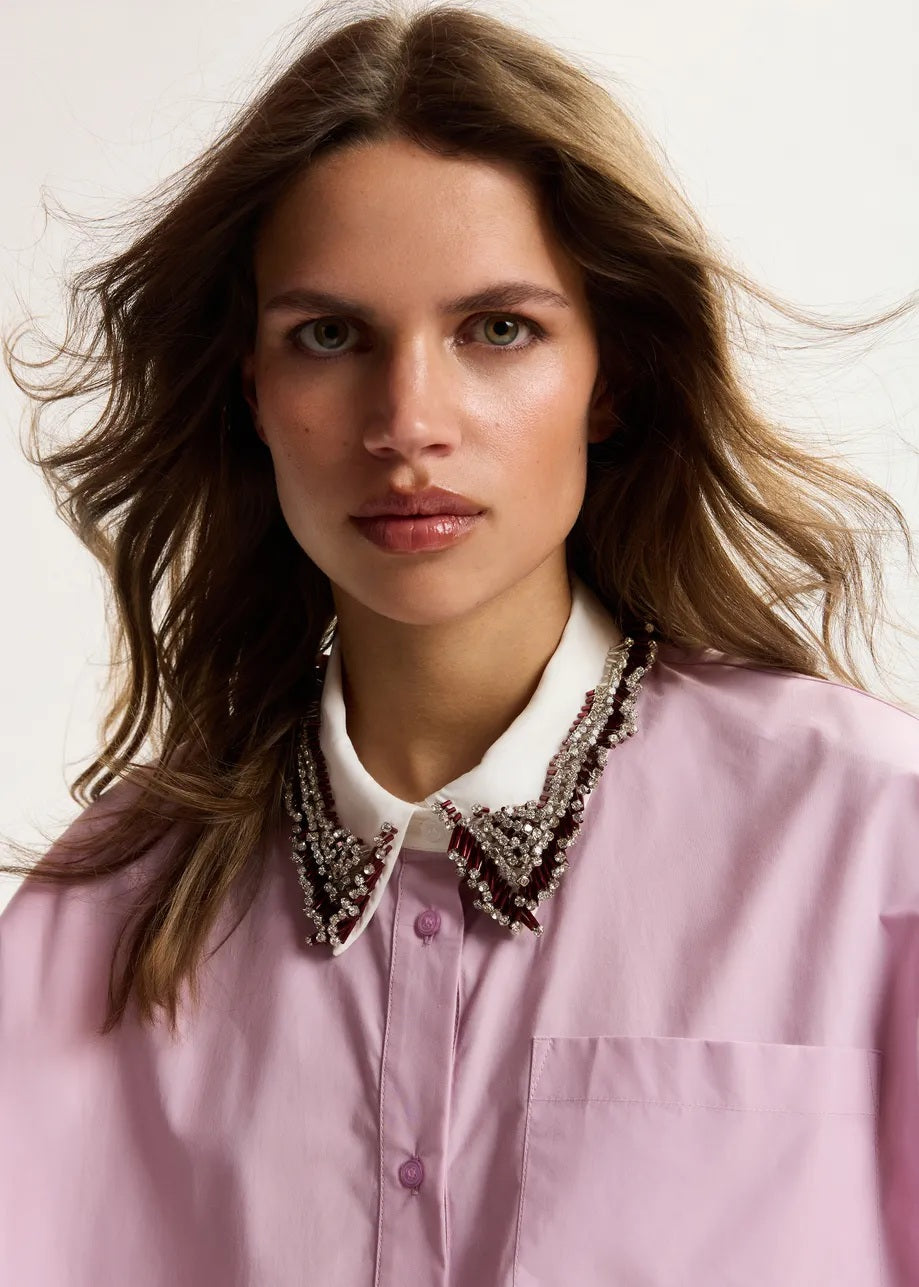 Bluse Essentiel Antwerp JANKY BEADED COLLAR SHIRT in rosa. Die Bluse aus 100% Baumwolle ist ein absolutes Style-Highlight. Die weite, kastenförmige Silhouette wird durch einen mit Perlen und Strasssteinen verzierten Kragen betont. Dies verleiht dem Look einen Hauch Glamours, während der elastische Saum dem Modell eine moderne Optik. Abgerundet wird das Design durch einen klassischen Knopfverschluss. Auf der Rückseite befindet sich eine feminine Kellerfalte. 