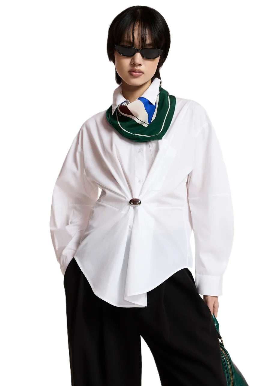 Bluse Essentiel Antwerp KREATIVE OVERSIZED SHIRT in weiß. Das Hemd aus Bio-Baumwolle besticht durch eine großzügige Silhouette mit einer sanft abgerundeten Naht. Die Bluse hat einen Hemdkragen und eine Brusttasche. Sie hat tief angesetzte Schultern und leicht voluminöse Ärmel. Abgerundet wird das Design mit geknöpften Manschetten und einer abnehmbaren Brosche. 