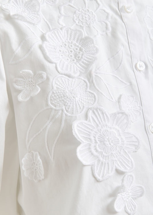 Bluse Essentiel Antwerp JORJA APPLIQUE FLOWER SHIRT in weiß. Die Bluse hat einen Stehkragen und eine Knopfleiste. Sie hat ebenfalls leichte Puffärmel mit Gummizug am Saum. Die Bluse hat wunderschöne Blumenstickereien auf der Vorderseite.