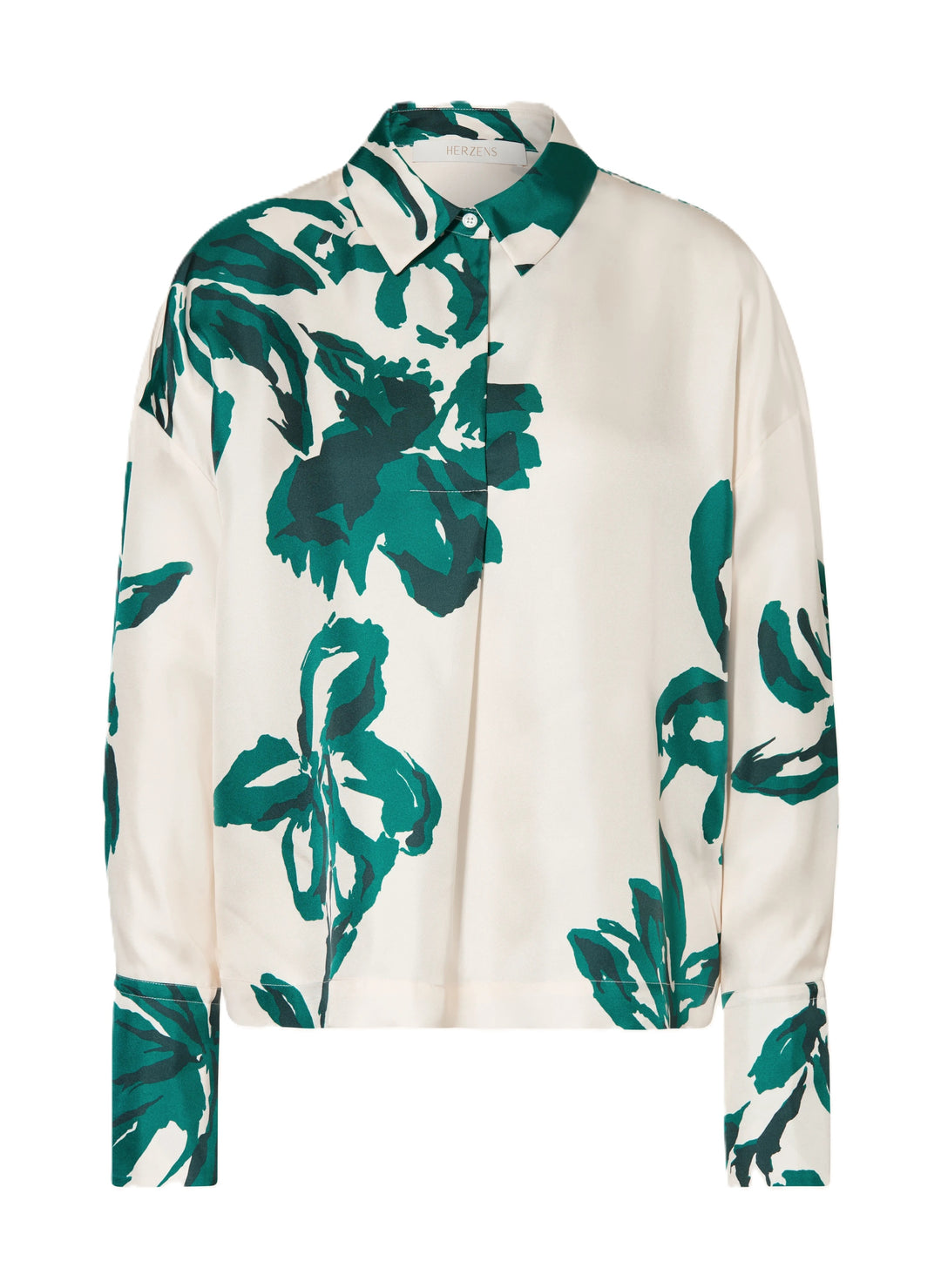 Bluse Herzens bottle green. Die hübsche Seidenbluse besticht durch ihr ausdrucksstarkes Muster. Der Unterton ist ecru und das Blumenmuster ist aus einem kräftigen Grünton. Die Bluse hat einen Kragen und eine halbe verdeckte Knopfleiste. Sie hat lange Ärmel mit breiten Manschetten und zwei Knöpfen. 