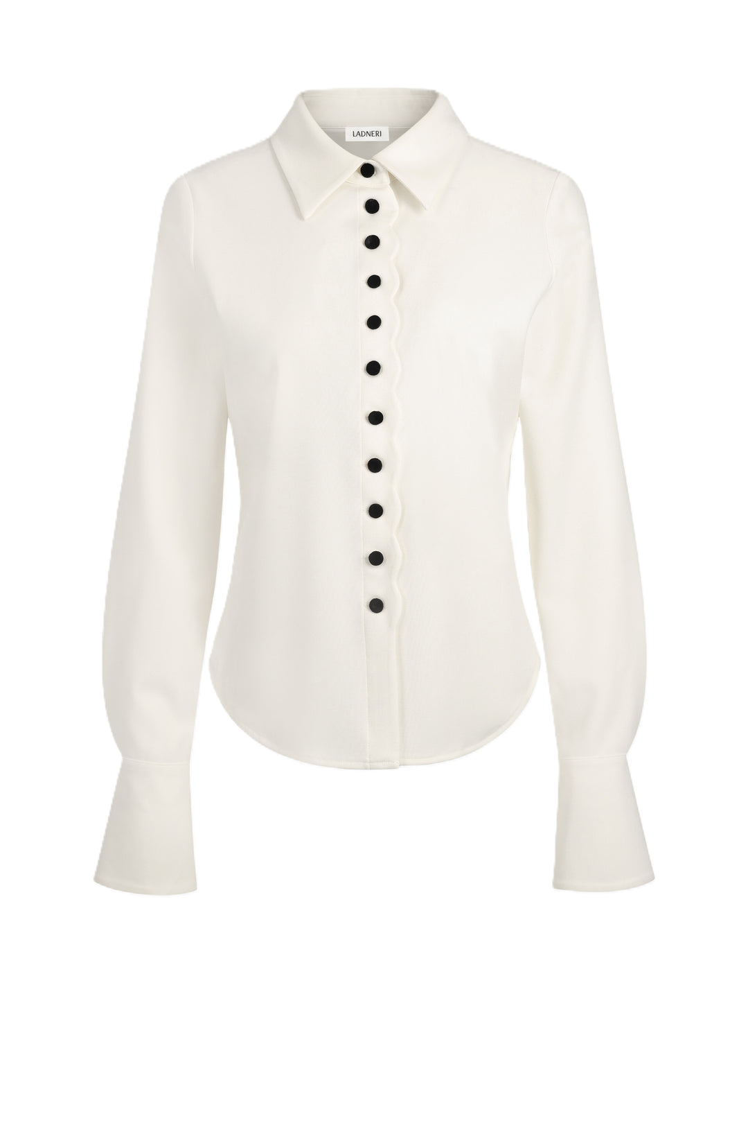 Bluse Ladneri Tala in ivory. Wunderschöne Bluse in ecru mit schwarzen Samtknöpfen. Die Bluse hat an der Vorderseite schöne Knöpfe, welche durch ein wellenförmiges Design abgerundet werden. Die Bluse hat große Manschetten und einen Kragen. Sie ist figurbetont geschnitten,.