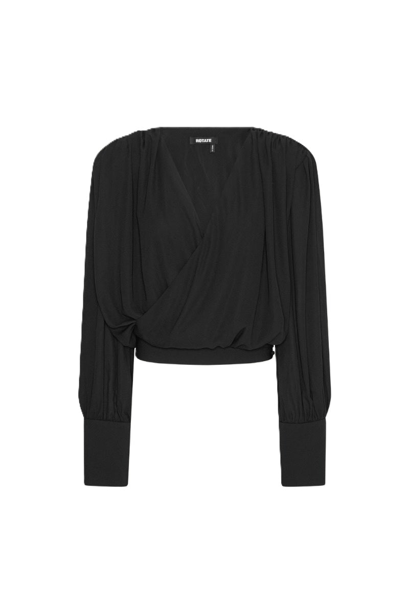 Bluse Rotate in schwarz. Die Bluse hat einen femininen V-Ausschnitt und überzeugt durch eine drapierte Wickeloptik vorne und gerafften Schultern. Die Bluse hat lange Ärmel mit breiten Manschetten. Die Bluse hat eine weiche Textur und einen eleganten Fall. Sie fällt groß aus.
