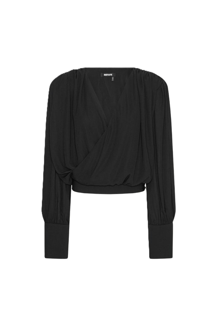 Bluse Rotate in schwarz. Die Bluse hat einen femininen V-Ausschnitt und überzeugt durch eine drapierte Wickeloptik vorne und gerafften Schultern. Die Bluse hat lange Ärmel mit breiten Manschetten. Die Bluse hat eine weiche Textur und einen eleganten Fall. Sie fällt groß aus.