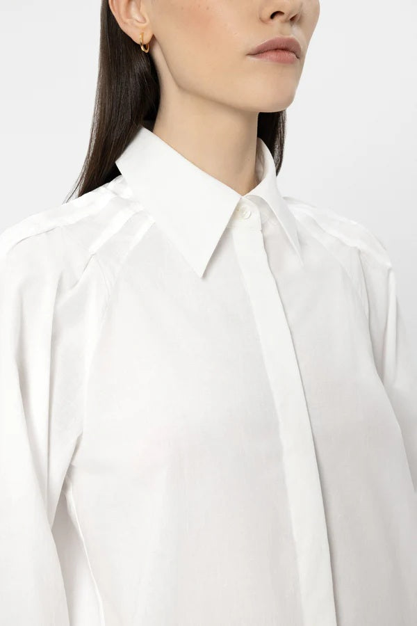 Bluse Luisa Cerano in weiß. Die feminine Hemdbluse besteht aus einer luftigen Baumwolle und hat voluminöse Ärmel. Sie hat eine verdeckte Knopfleiste, eine Rückenfalte und einen Kragen. Sie hat feminine Raffungen.