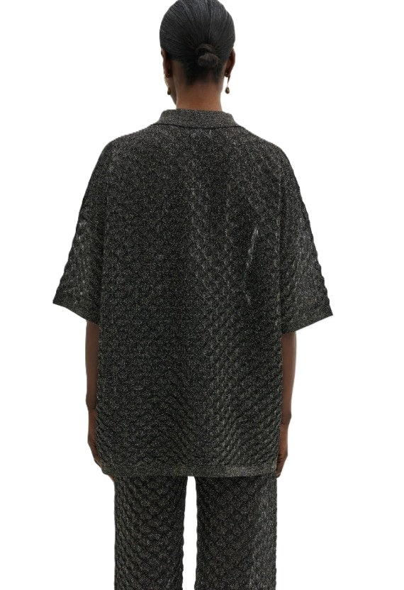 Bluse Malina Moa Oversized Pointelle Knitted Shirt in schwarz. Kurzarm-Strickhemd mit filigranem Muster. Das Hemd hat einen metallischen Schimmer in schwarz und ist aus Feinstrick gewebt. Es hat eine Knopfleiste auf der Vorderseite und einen Kragen.
