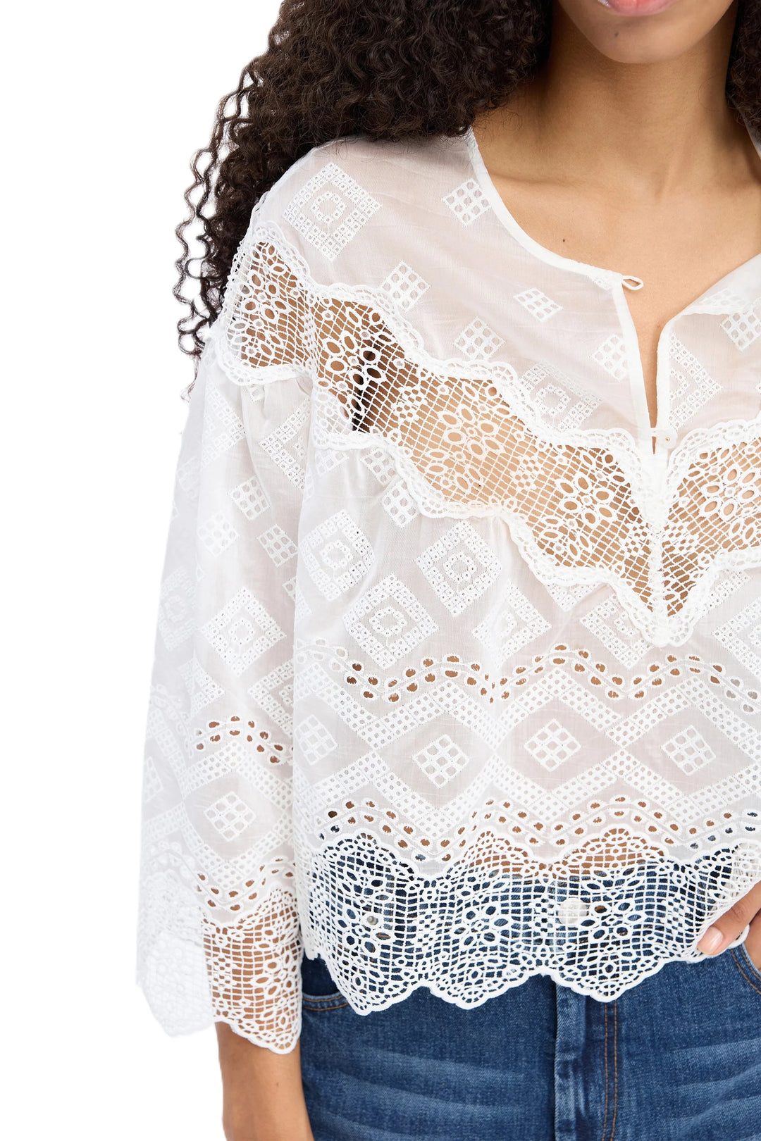 Bluse Munthe VALIANCE in weiß. Wunderschöne transparente Spitzenbluse mit dekorativem Spitzenmuster. Die Bluse hat 3/4-Ärmel mit sanftem Volumen, einen runden Ausschnitt mit Knopfverschluss hinten sowie Bogenkanten für einen femininen und eleganten Look.