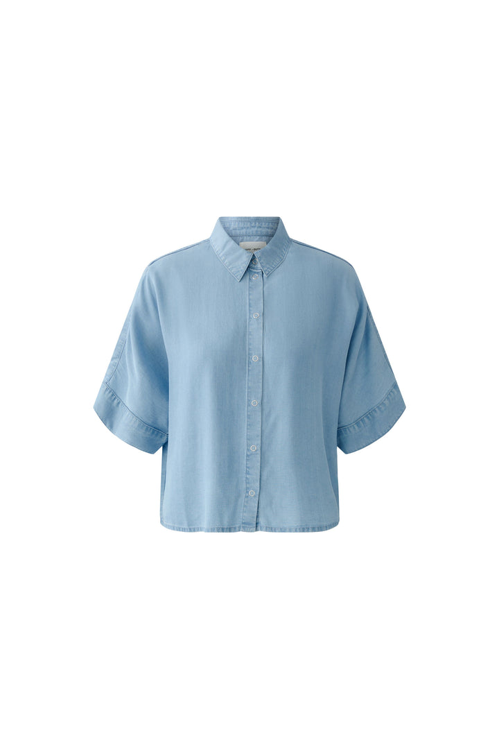 Bluse Oui. Schöne und sommerliche Halbarmbluse aus 100% Lyocell Denim. Die Bluse ist lässig geschnitten und hat eine reguläre Länge. Sie hat einen Kragen und eine Druckknopfleiste. Die Bluse hat einen weiten Kurzarm. Die Ärmel sind angeschnitten. Es befinden sich Kellerfalten links und rechts an der Rückenpasse. 