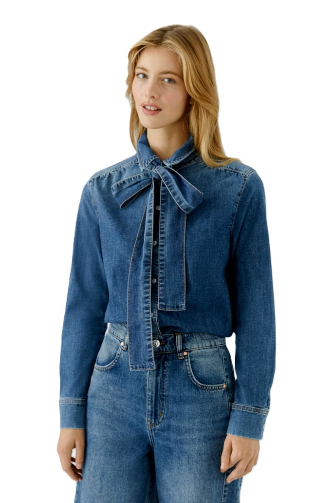 Coole Jeansbluse von Oui in Denim. Die Bluse hat eine abknöpfbare Schluppe, die man schön zur Schleife binden kann. Die Bluse hat Perlmuttdruckknöpfe und ist normal geschnitten. 