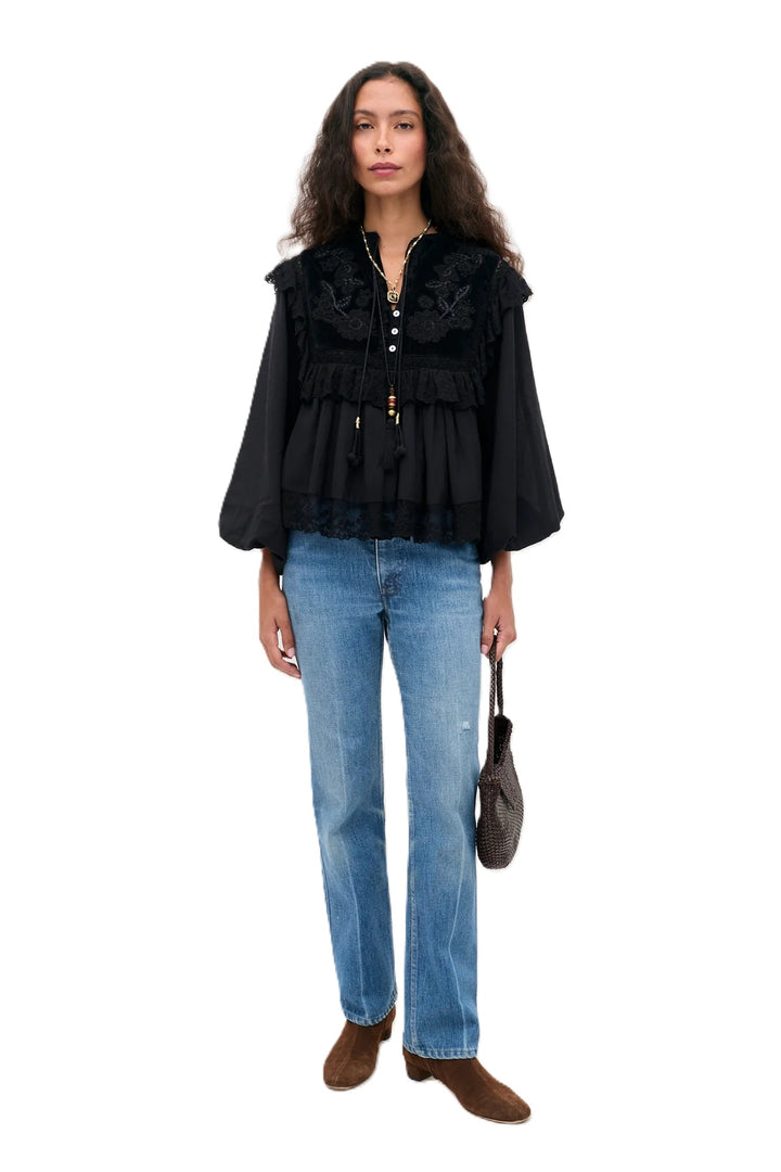 Bluse Rixo Diann Top in black. Ganz besondere Bluse in schwarz. Die Bluse hat einen verspielten romantischen Look mit Spitze und Samt. Die Bluse ist aufwendig mit Stickereien bestickt und hat kleine Spitzenflügel an den Schultern. Die Ärmel sind lang und haben eine Gummimanschette zum Hochshoppen. Sie hat einen V-Ausschnitt mit kleinen Knöpfen und Bändern mit Kordeldetails. 