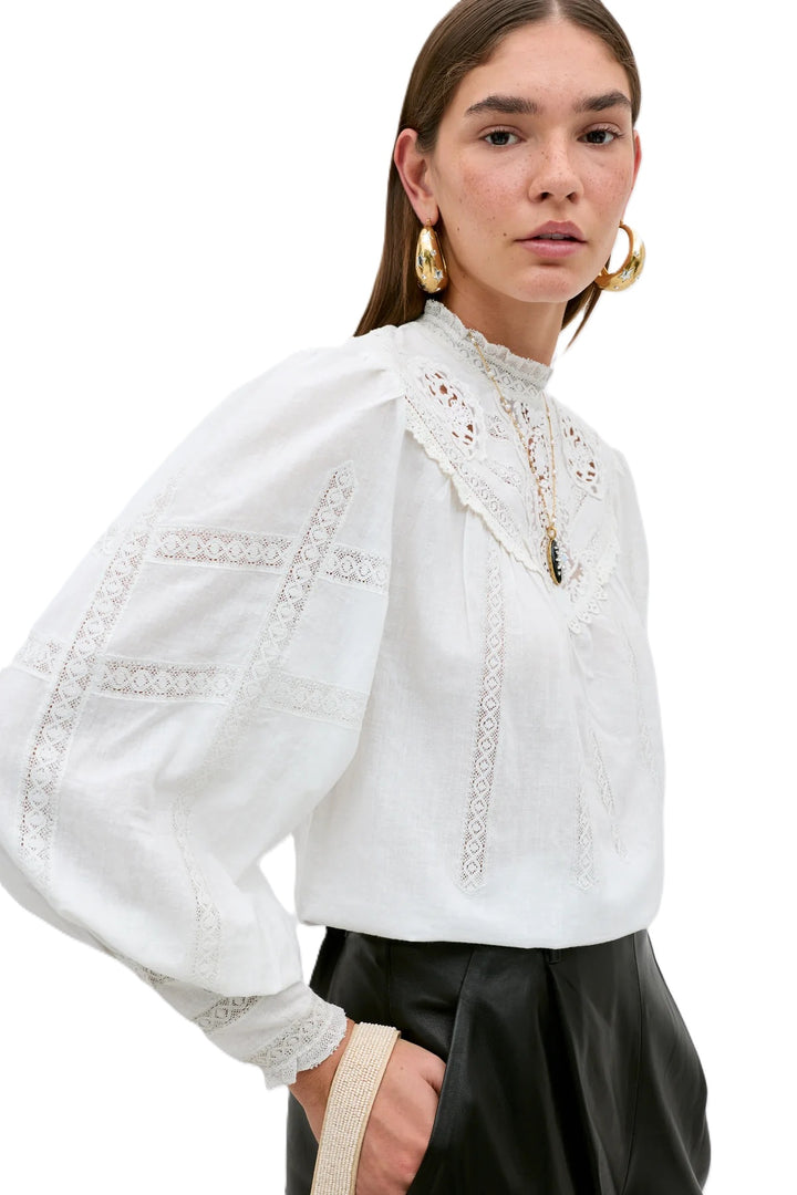 Bluse Rixo Tamzin Top in cream. Super schöne und moderne Bluse mit femininen allover Spitzendetails. Die Bluse hat Knöpfe auf der Rückseite. Sie hat einen Stehkragen und kann schön in die Hose gesteckt werden. Die Ärmel sind lang mit breiter Spitzenmanschette.