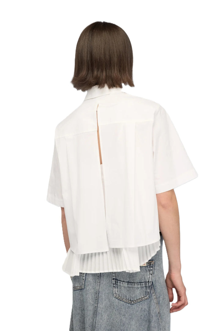 Bluse Semicouture CAMICIA DOMINGA. Super schöne weiße Bluse mit kurzarm. Die Bluse hat eine aufgesetzte Brusttasche, Kragen und Knopfleiste. Das Highlight befindet sich auf der Rückseite. Die Bluse hat einen kompletten Schlitz auf der Rückseite. Der obere Teil ist offen und gleichzeitig ist ein Unterteil angenäht, welches in Falten gelegt ist. Der hintere Teil der Bluse ist länger geschnitten.