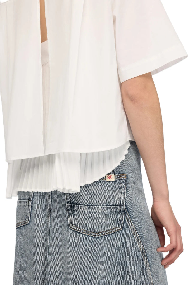 Bluse Semicouture CAMICIA DOMINGA. Super schöne weiße Bluse mit kurzarm. Die Bluse hat eine aufgesetzte Brusttasche, Kragen und Knopfleiste. Das Highlight befindet sich auf der Rückseite. Die Bluse hat einen kompletten Schlitz auf der Rückseite. Der obere Teil ist offen und gleichzeitig ist ein Unterteil angenäht, welches in Falten gelegt ist. Der hintere Teil der Bluse ist länger geschnitten.
