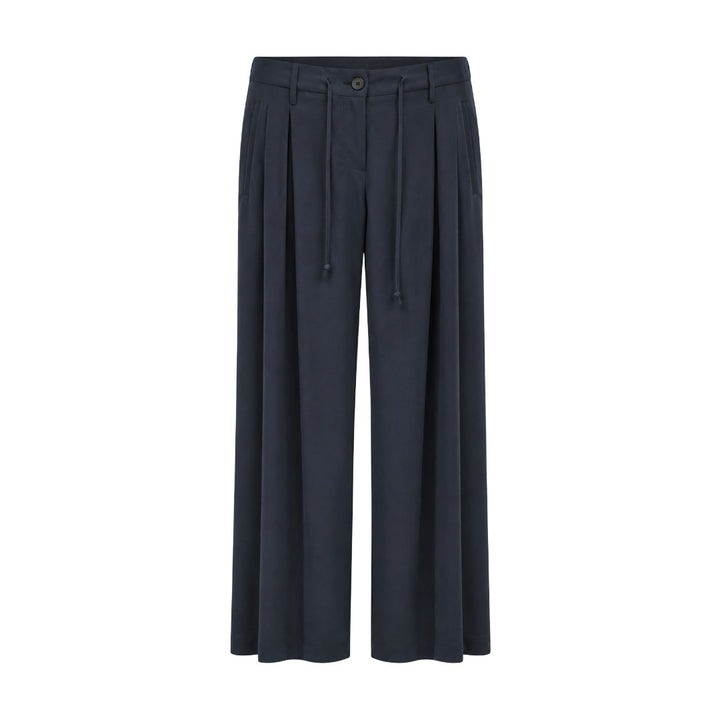 Hose Narli in Night Blau. Aus Schurwolle mit Stretch-Anteil mit geschmeidigen Qualität und einem fließenden Fall. Die Hose hat ein langes und weites Bein mit nicht auftragenden Bundfalten. Verdeckte Knopfleiste und  Zugband im Bund eingearbeitet. Auf der Rückseite befinden sich Stecktaschen und seitlich schräge Eingriffstaschen.