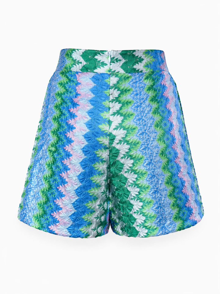 Shorts Pho Firenze in blau und grün. Schöne sommerliche Bermuda im bekannten Zickzack-Print. Die Bermuda hat einen festen Bund und Taschen. Die Beinweite ist leicht ausgestellt. Das zarte Glitzergarn lässt die Hose feminin und edel erscheinen. Die Hose hat einen Zip auf der Rückseite. Der Tragekomfort ist sehr hoch.