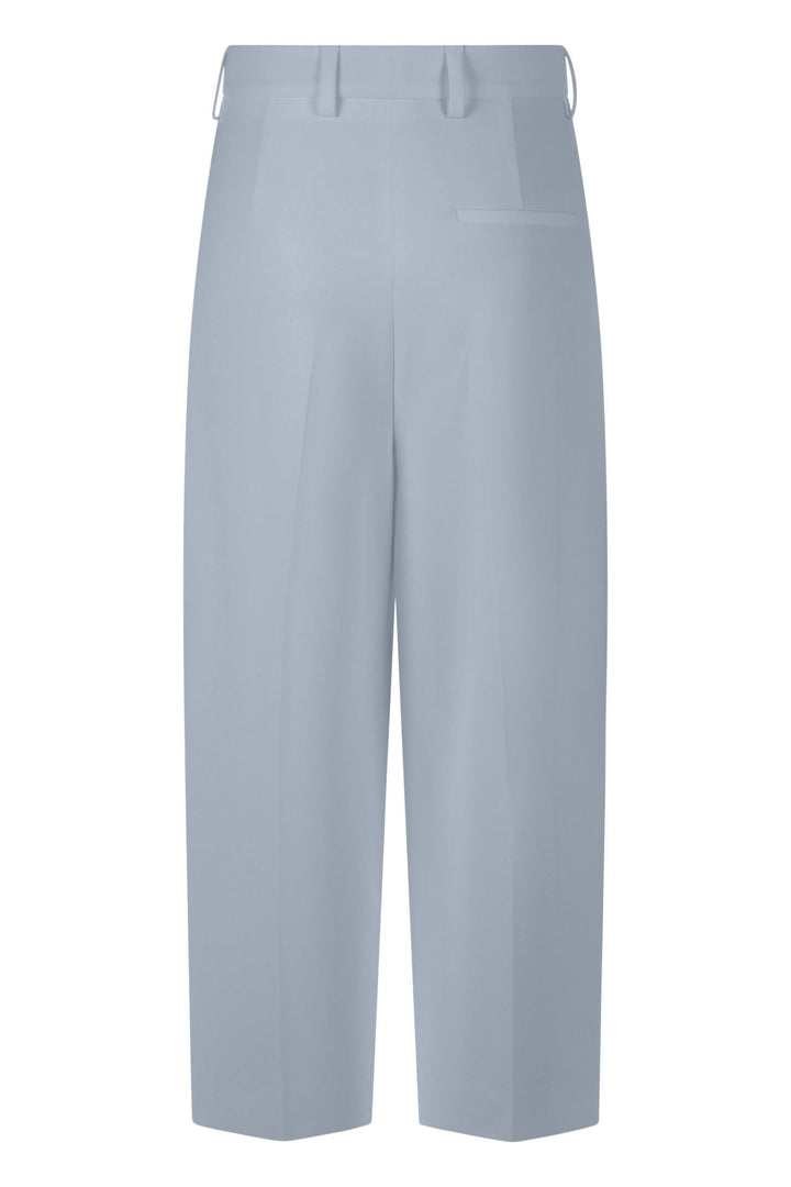 Hose Rossi Noa Crop. Coole Hose in verkürzter Form. Die Hose hat Bundfalten und einen verstellbaren Innenbund. Sie ist High-Waist geschnitten und hat ein verkürztes Bein. Der leichte O-Shape verleiht der Hose einen modernen Look. Die Hose hat schräge Eingriffstaschen und eine Leistentasche auf der Rückseite in hellblau.