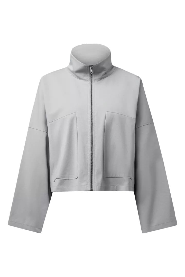 Jacke Drykorn ELSTOW_1 10 in grau. Die coole Jacke ist kurz und kastig geschnitten. Sie hat einen hohen Kragen und einen Zip zum Verschließen. Die Jacke hat große aufgesetzte Taschen. Das Design kombiniert eine kurze Rückenlänge mit weiten Ärmeln. Die Jacke hat überschnittene Schultern und fällt groß aus. 