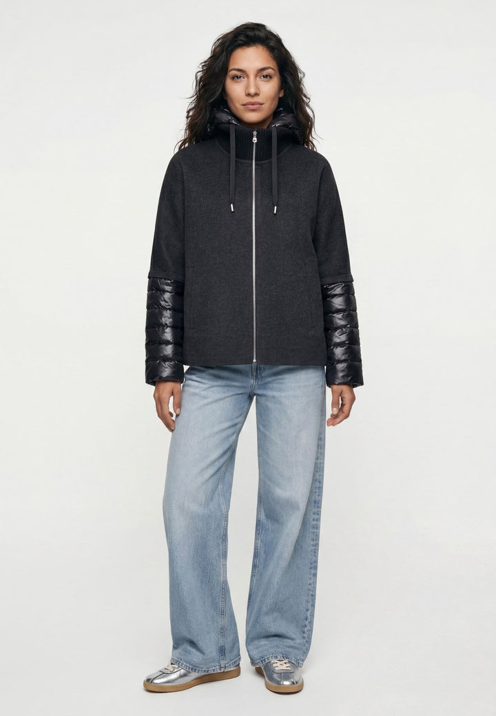 Jacke Milestone MSAzalea in anthrazit. Schöne Jacke mit zweierlei Stoffmix. Die Jacke besteht aus Wolle Doubleface und Stepp. Sie hat eine leichte A-Form und einen dekorativen Stehkragen aus Strick. Die Jacke hat eine abnehmbare Kapuze aus Nylon mit Tunnelzug. Die Ärmel sind aus Nylon gesteppt. Sie hat einen Metall-Reißverschluss in der vorderen Mitte und Eingriffstaschen.