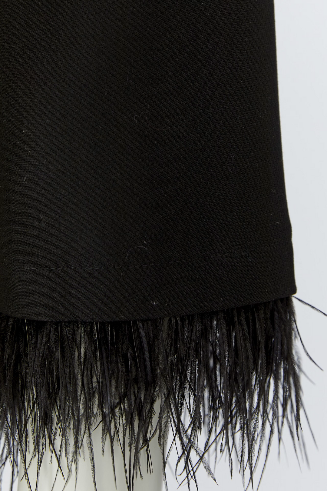 Jacke Oui in Schwarz. Kurzer Balloon Fit mit voluminöser O-Shape-Silhouette. Abknöpfbare Kunstfedern an den Ärmelsäumen. Kragenloser Rundhalsausschnitt und Knopfleiste mit funkelnden Strassknöpfen. Seitliche Eingriffstaschen.