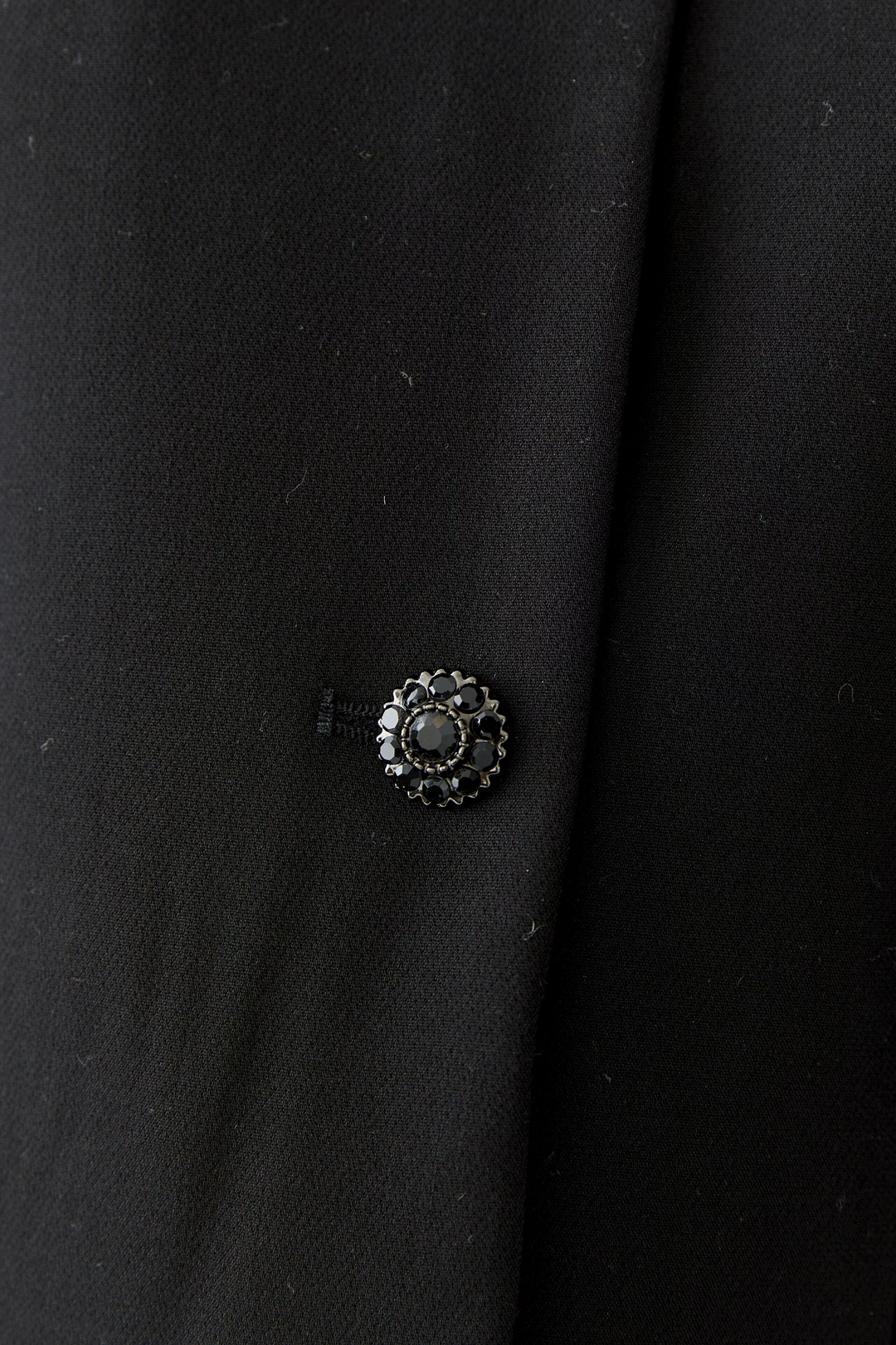 Jacke Oui in Schwarz. Kurzer Balloon Fit mit voluminöser O-Shape-Silhouette. Abknöpfbare Kunstfedern an den Ärmelsäumen. Kragenloser Rundhalsausschnitt und Knopfleiste mit funkelnden Strassknöpfen. Seitliche Eingriffstaschen.