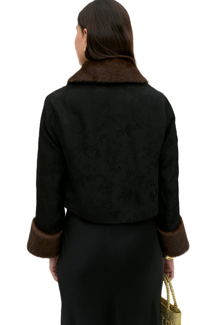 Jacke Rixo Luanne. Jacke in schwarz mit dezentem Paisleymuster. Die Jacke hat am Kragen und an den Manschetten ein Fakepelzbesatz. Die Jacke kann mit Knöpfen auf der Vorderseite verschlossen werden.