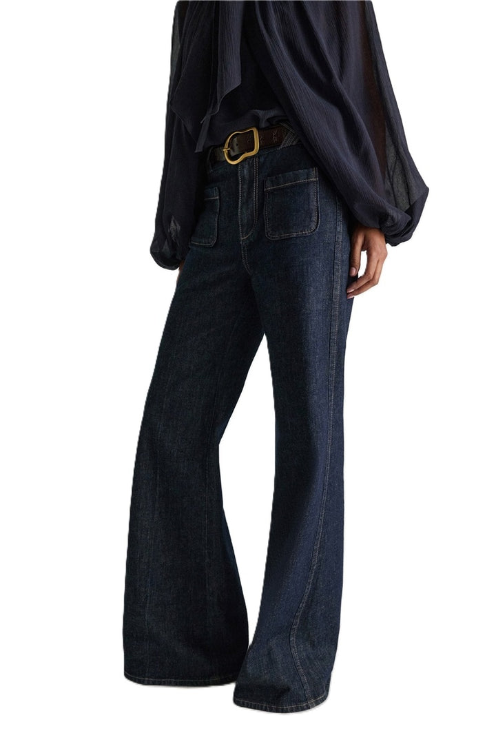 Jeans Dorothee Schumacher DENIM LOVE Pants in dark denim. Die ausgestellte dunkelblaue Jeans besticht durch ihre aufgesetzten Taschen vorne und braided Details am Bund. Dadurch bekomt die Jeans einen modernen Retro-Look. Der schmale Schnitt wird durch einen Signature-Knopf abgerundet. Die Jeans hat einen Kick und Bügelfalten. Auf der Rückseite befinden sich Pattentaschen.