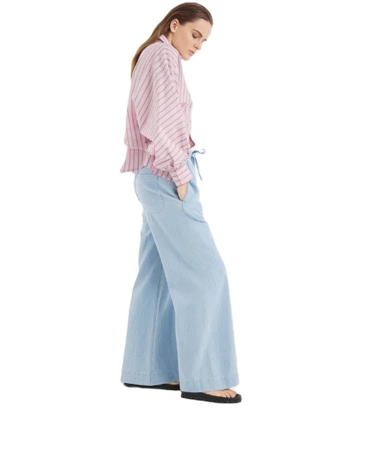 Jeans SO SUE Anna Pants light Denim. Die Anna Pants in Light Blue ist die perfekte Kombination aus Denim-Look und sommerlicher Leichtigkeit. Gefertigt aus feinem Denim Chambray, fühlt sie sich weich, fließend und angenehm kühl auf der Haut an. Die Jeans hat einen Gummibund und einen Tunnelzug zum Justieren. Sie hat Taschen und ein weites lässiges langes Bein.