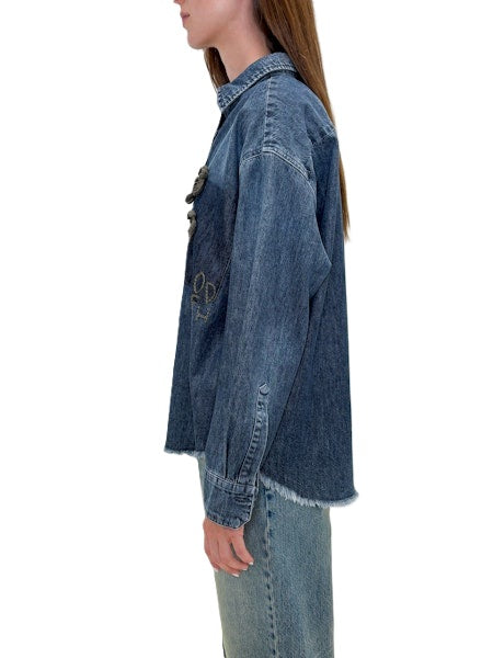 Jeansjacke von Odeeh in blau mit Blumenstickerei und Odeehlogo auf der Brust. Die Jacke hat einen Kragen,, Knöpfe und ausgefranste Säume. Sie fällt normal aus. 