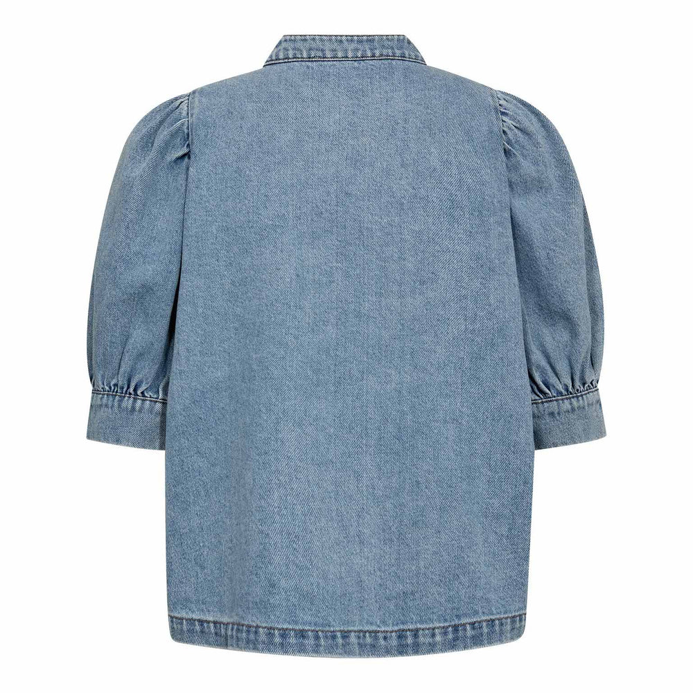 Jeansbluse Co'Couture AsjaCC Denim Blouse. Feminine Jeansbluse in blau mit kleinen Puffärmeln. Die Bluse hat einen Stehkragen und Metallknöpfe. Ebenfalls seitliche schräge Taschen. Wir haben auch den passenden Hosenrock dazu.