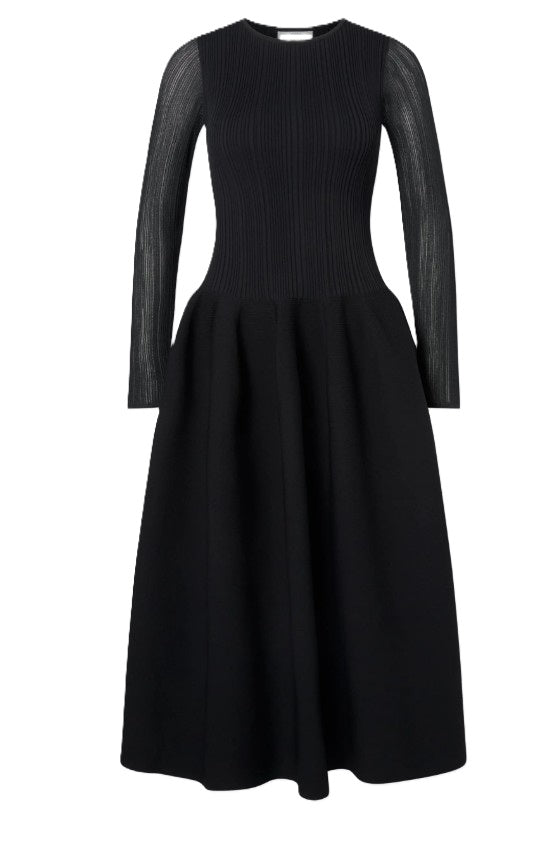 Kleid Malina Elona Voluminous Skirt Knitted Midi in schwarz. Geripptes Midikleid mit voluminösem Rock. Das Kleid hat ein figurbetontes Oberteil. Es hat einen femininen Rundhalsausschnitt. Die Ärmel sind leicht transparent. Die Taille ist betont und der Rock voluminös geschnitten und mittellang.