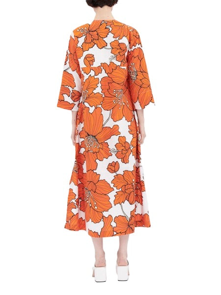 Kleid von Odeeh in mittellang mit große Blumenmuster in orange. Das Kleid hat eine halbe Knopfleiste und aufgesetzte Taschen. Es hat 3/4 Ärmel und ist weit geschnitten. 