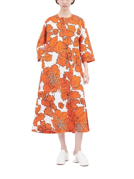 Kleid von Odeeh in mittellang mit große Blumenmuster in orange. Das Kleid hat eine halbe Knopfleiste und aufgesetzte Taschen. Es hat 3/4 Ärmel und ist weit geschnitten. 