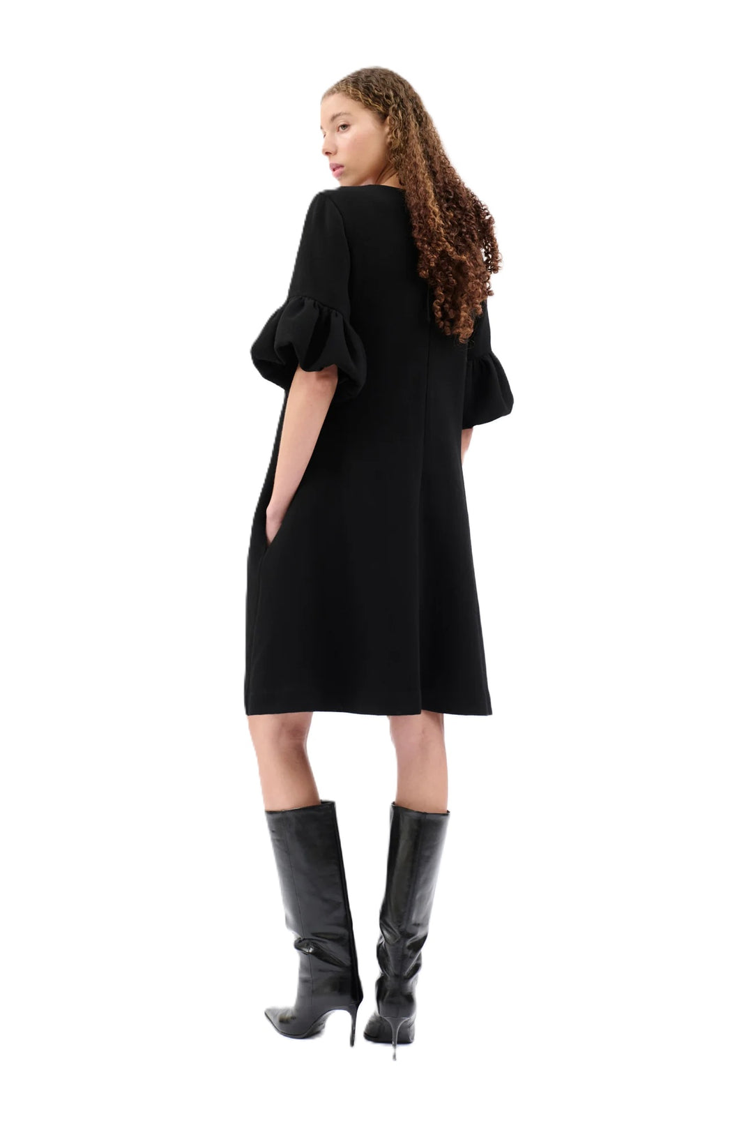 Kleid Odeeh in schwarz. Kleid mit ausgestelltem Rockteil und Rundhalsausschnitt. Der Reißverschluss befindet sich auf der Rückenmitte. Das Kleid ist knielang und hat einen femininen Tulpenärmel mit Volants. Eingriffstaschen runden das Design ab.