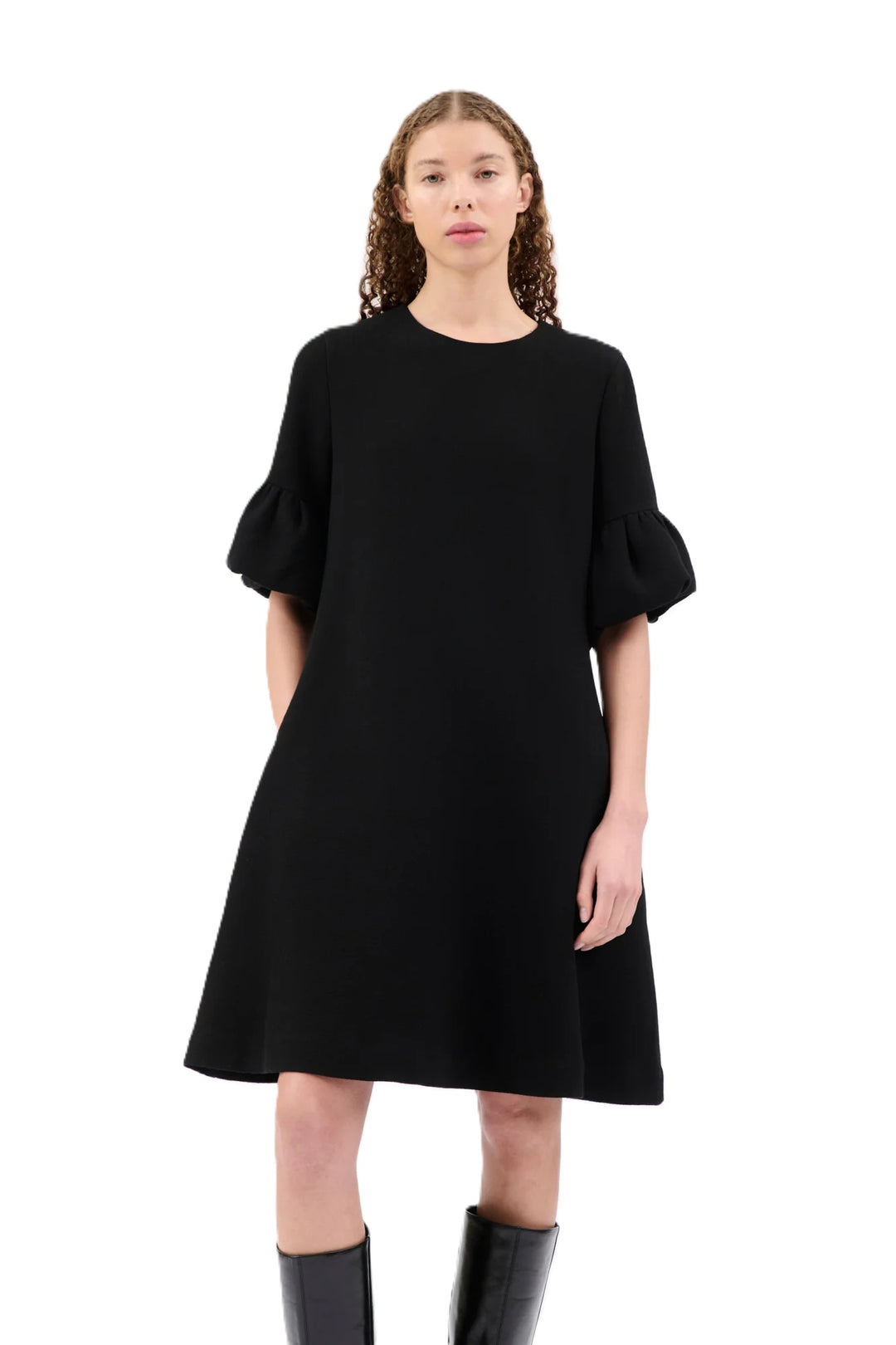 Kleid Odeeh in schwarz. Kleid mit ausgestelltem Rockteil und Rundhalsausschnitt. Der Reißverschluss befindet sich auf der Rückenmitte. Das Kleid ist knielang und hat einen femininen Tulpenärmel mit Volants. Eingriffstaschen runden das Design ab.