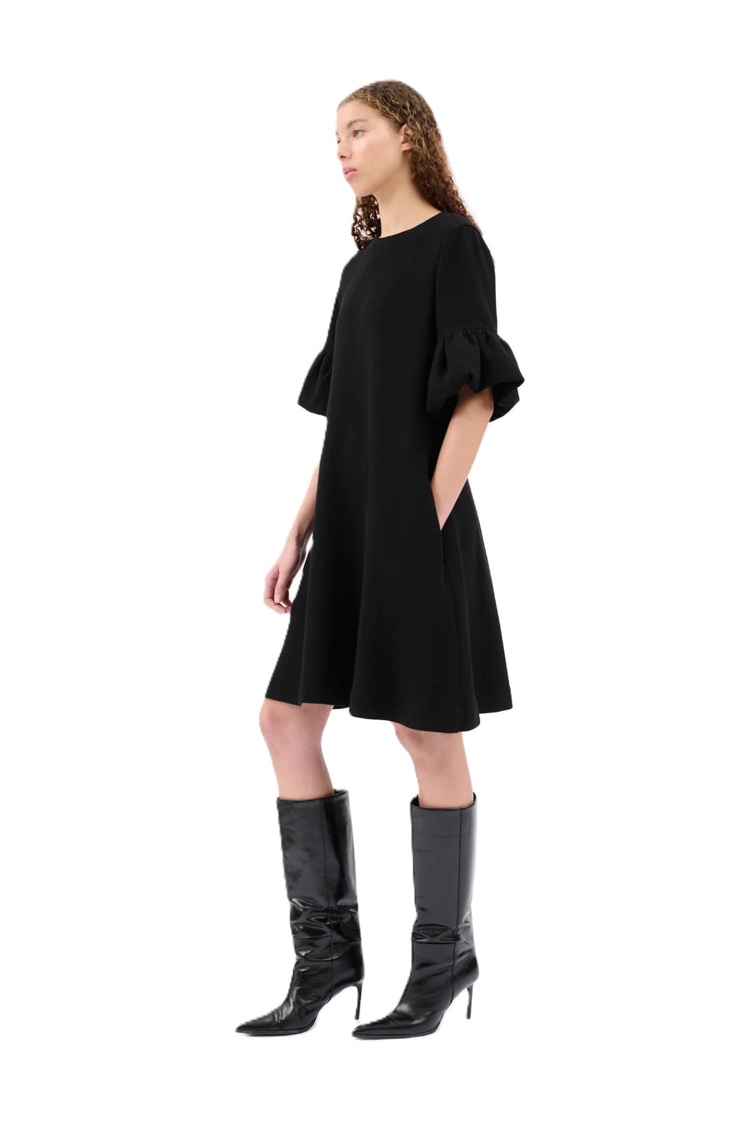 Kleid Odeeh in schwarz. Kleid mit ausgestelltem Rockteil und Rundhalsausschnitt. Der Reißverschluss befindet sich auf der Rückenmitte. Das Kleid ist knielang und hat einen femininen Tulpenärmel mit Volants. Eingriffstaschen runden das Design ab.