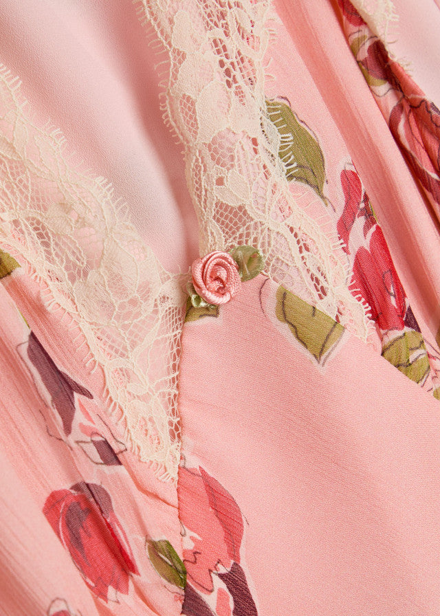 Kleid Rixo. Wunderschönes Kleid mit Blumenprint. Am Ausschnitt und am Ärmel ist das Kleid mit Spitze verziert. Am V-Ausschnitt wurde noch eine hübsche zarte Rose plaziert. Das Kleid hat einen kleinen Gürtel und ist lang geschnitten.