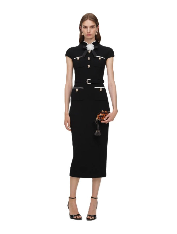 Kleid Self-Portrait in schwarz. Dieses elegante Midikleid begeistert mit einer figurbetonten Silhouette und edlen Details. Die dekorative Schleife mit Blumenbrosche am Kragen, kontrastierende Besätze sowie goldene Knöpfe mit Perlenverzierung verleihen dem Design eine besonders luxuriöse Ausstrahlung. Aufgesetzte Taschen