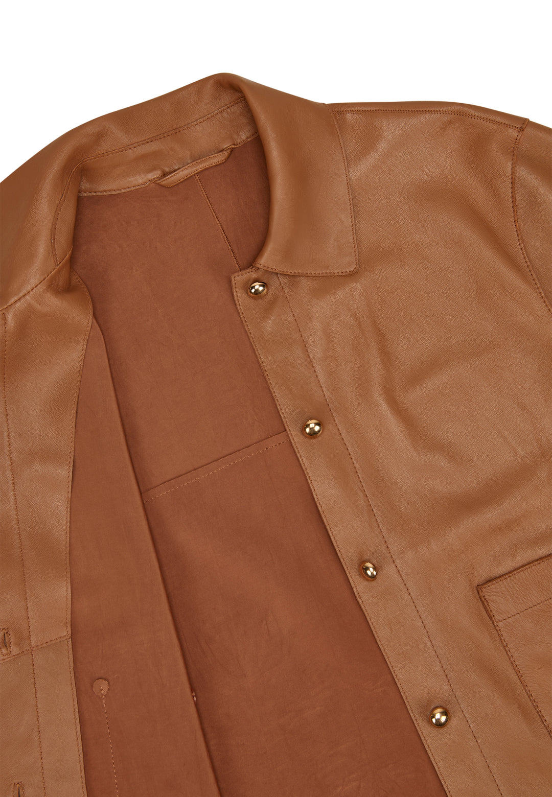 Jacke Milestone MSBetty in cognac. Wunderschöne Jacke aus feinem Lamm Nappa. Die Jacke ist bondiert mit tonigem Lycra Jersey. Sie ist geschnitten wie ein kurzes Hemd mit Knöpfen. Die Form ist gerade. Die Jacke hat einen Hemdkragen und einen Knopfverschluss. Ebenso zwei aufgesetzte Taschen mit Knopf. Die Ärmel sind kurz und die Schultern leicht überschnitten. An der Seitennaht befindet sich ein kleiner Schlitz. 