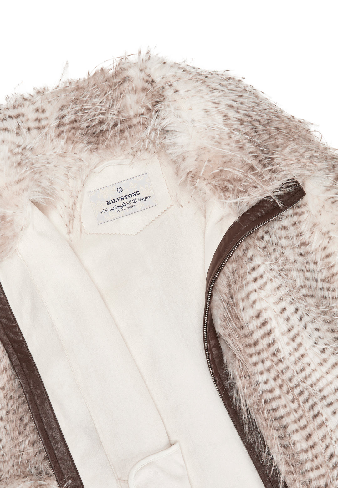 Jacke Milestone MSDoloria in beige. Das Cape hat eine überschnittene Schulter und ist aus Kunstpelz in zweifarbigem langhaarigen Federlook gefertigt. Der Kunstpelz ist gebondet mit Velours. Das Cape hat einen Stehkragen und einen Reißverschluss in der vorderen Mitte. Das Cape hat Leistentaschen und einen Tunnelzug mit elastischer Kordel am Saum.